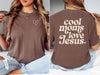 Model wearing Cool Moms Love Jesus T Shirt with heart design, showcasing faith and motherhood style.