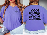 Model wearing a purple Cool Moms Love Jesus T Shirt with heart design, showcasing trendy mom life.