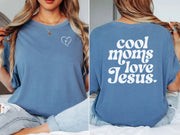 Cool Moms Love Jesus T Shirt displayed on a model, featuring heart design and text on a soft blue fabric.