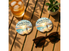 Journey With Jesus Adventure Awaits Car Coaster on a wooden table with sunglasses and a drink.