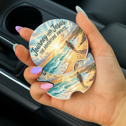 Journey With Jesus Adventure Awaits Car Coaster held in hand with a beach theme and serene colors.