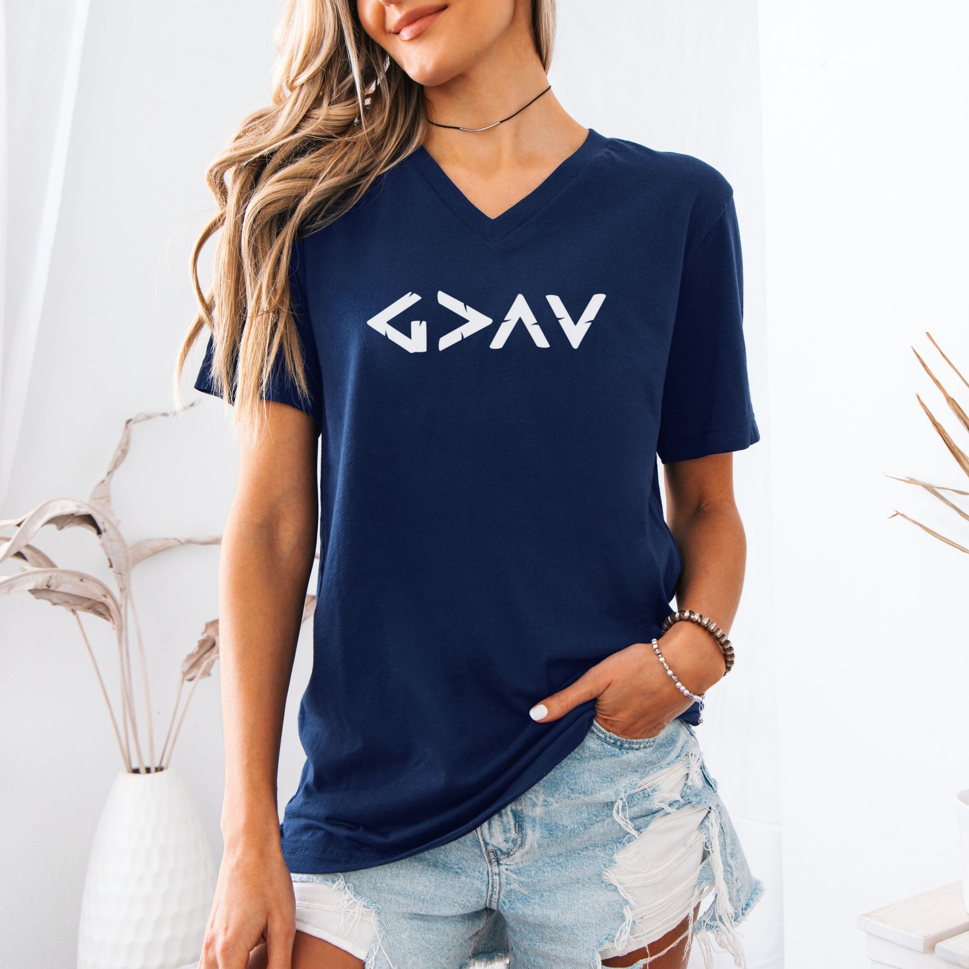 God Is Greater Than Highs And Lows V Neck Tee displayed on a model, representing faith with a minimalist design.