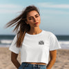 This Mama Prays Christian Crop Tee for Moms worn by a woman at the beach with wind-blown hair and a confident pose.