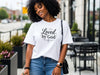Woman wearing a Loved by God T-Shirt outdoors, showcasing faith and comfort in casual style.