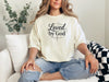 Woman wearing a Loved by God T-Shirt, showcasing a stylish design and comfortable fit.