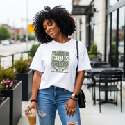 Model wearing a Placed in God's Hands T-Shirt, enjoying coffee outside in a casual urban setting.