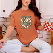 Woman wearing a Placed in God's Hands T-Shirt while holding a checkered cup in a cozy kitchen.
