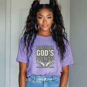 A woman wearing a violet Placed in God's Hands T-Shirt with hands graphic, promoting trust in God.
