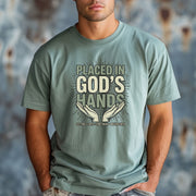 Model wearing Placed in God's Hands T-Shirt featuring hands graphic, symbolizing faith and trust in God.