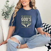 Model wearing Placed in God's Hands T-Shirt, showcasing its comforting message and stylish design.