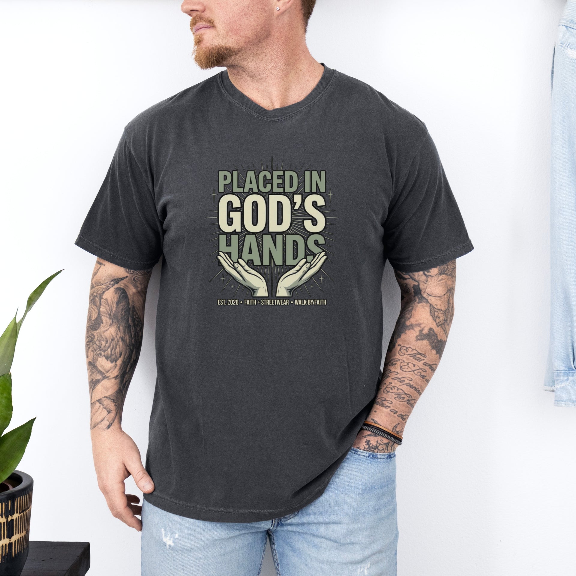 Placed in God's Hands T-Shirt worn by a man, featuring a design with hands and a comforting message of faith.