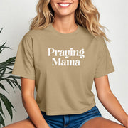 Woman wearing Praying Mama Crop Tee with trendy design, sitting against a neutral background.