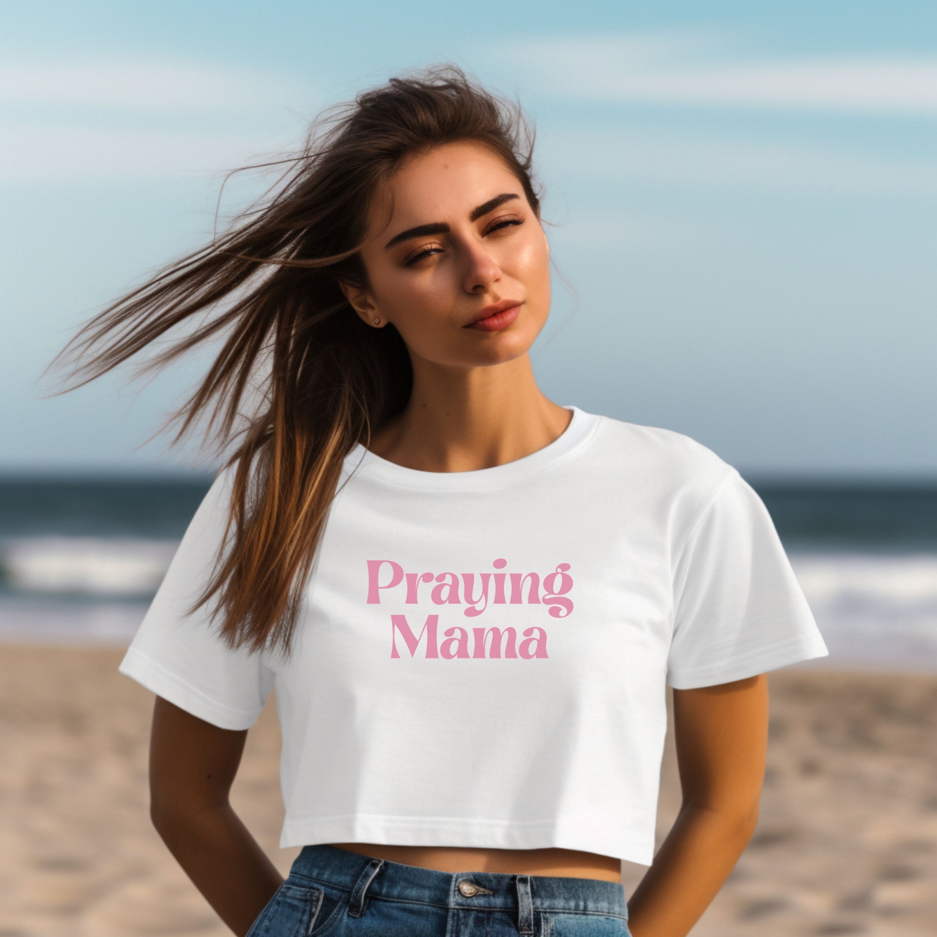 Model wearing a Praying Mama Crop Tee on the beach, showcasing the trendy design and stylish fit.