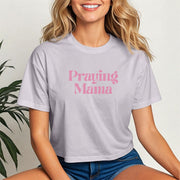 Woman wearing a light purple Praying Mama Crop Tee, showcasing a stylish script design for faith-filled moms.