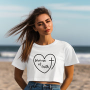 Woman Of Faith Heart Cross Crop Tee worn by a woman on the beach, featuring a heart and cross design.