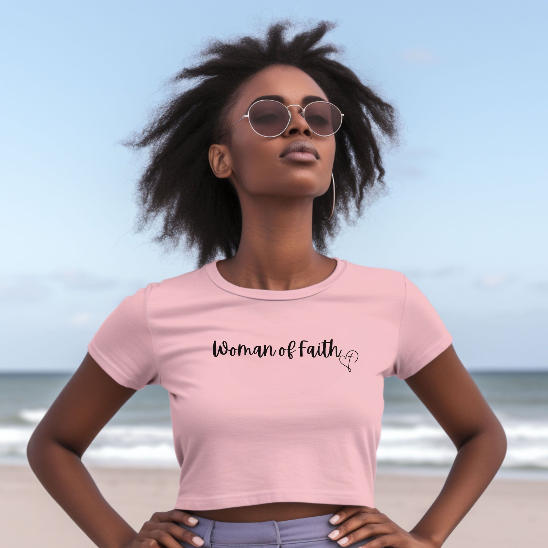 Woman Of Faith Crop Tee worn by a confident woman against a beach background, showcasing a stylish and minimal design.