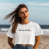 Woman Of Faith Crop Tee model wearing a cropped white t-shirt with a stylish script design at the beach.