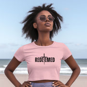 Model wearing a pink Redeemed Cross Graphic Crop Tee on the beach with sunglasses.