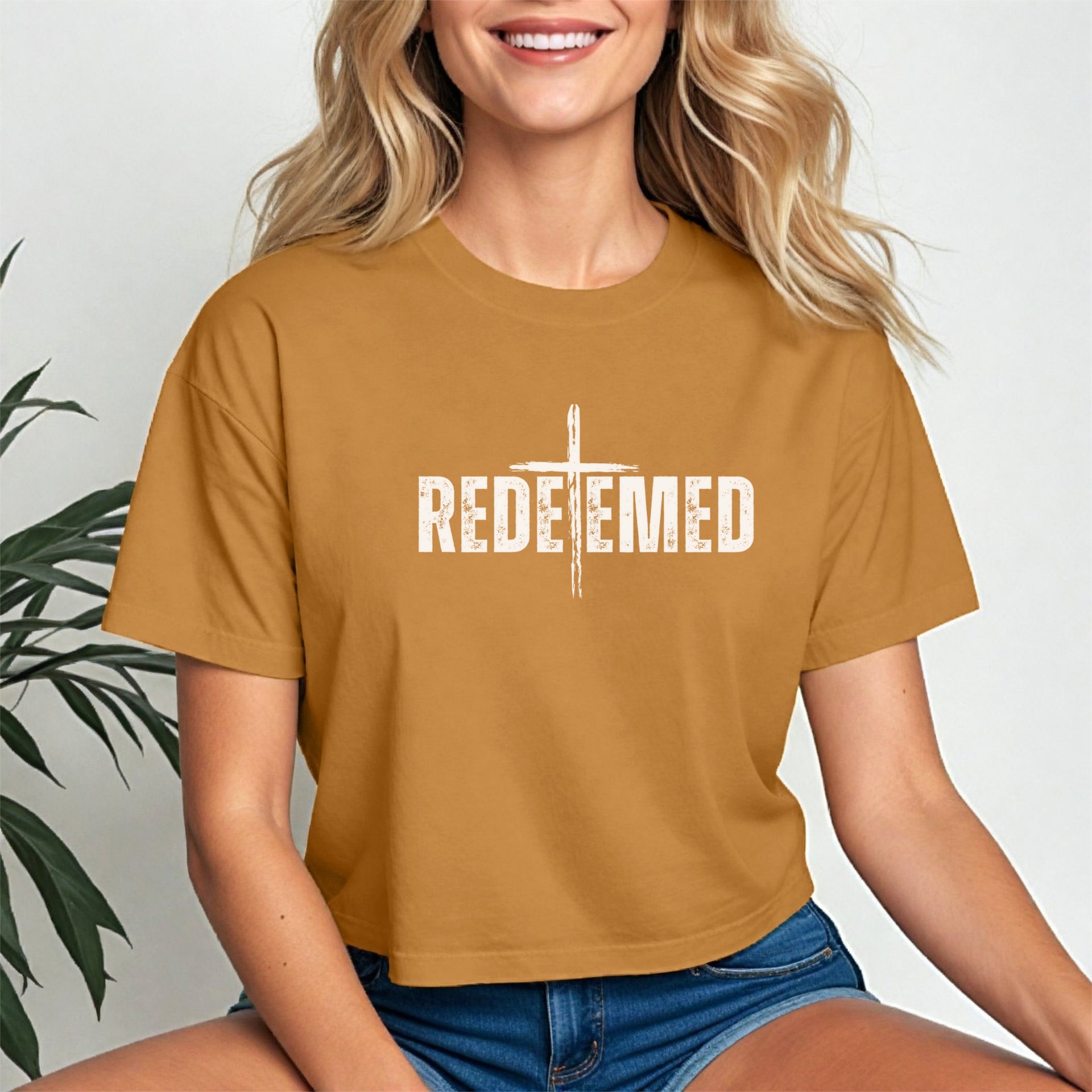 Model wearing a Redeemed Cross Graphic Crop Tee in camel color, featuring a cross design centered on the front.