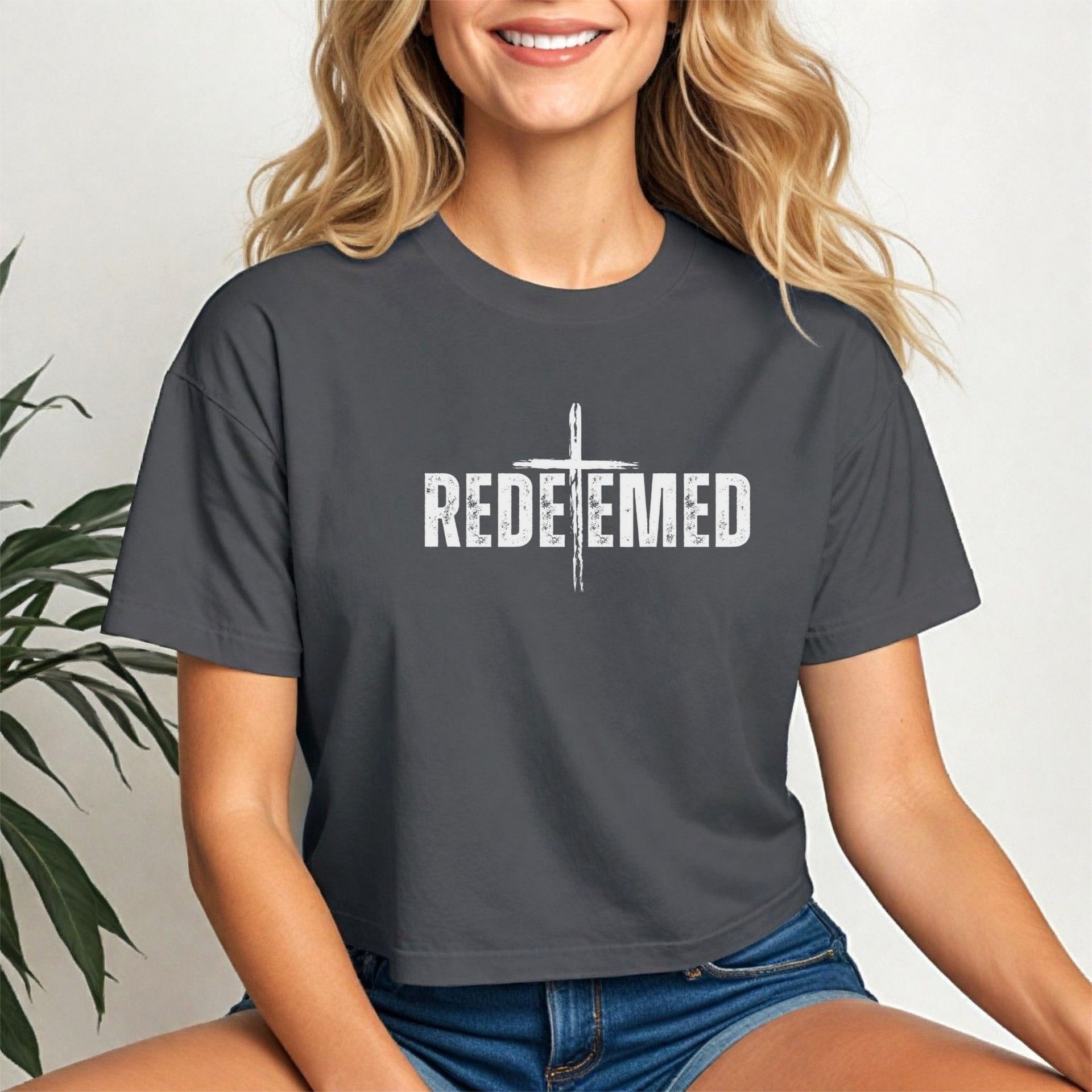 Redeemed Cross Graphic Crop Tee displayed on a smiling woman, featuring a trendy cropped fit and meaningful cross design.