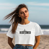 Woman at the beach wearing Redeemed Cross Graphic Crop Tee with cross design.