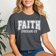 Faith Ephesians 2 8 Crop Tee displayed on a smiling woman, featuring bold text on a coal short-sleeve tee.