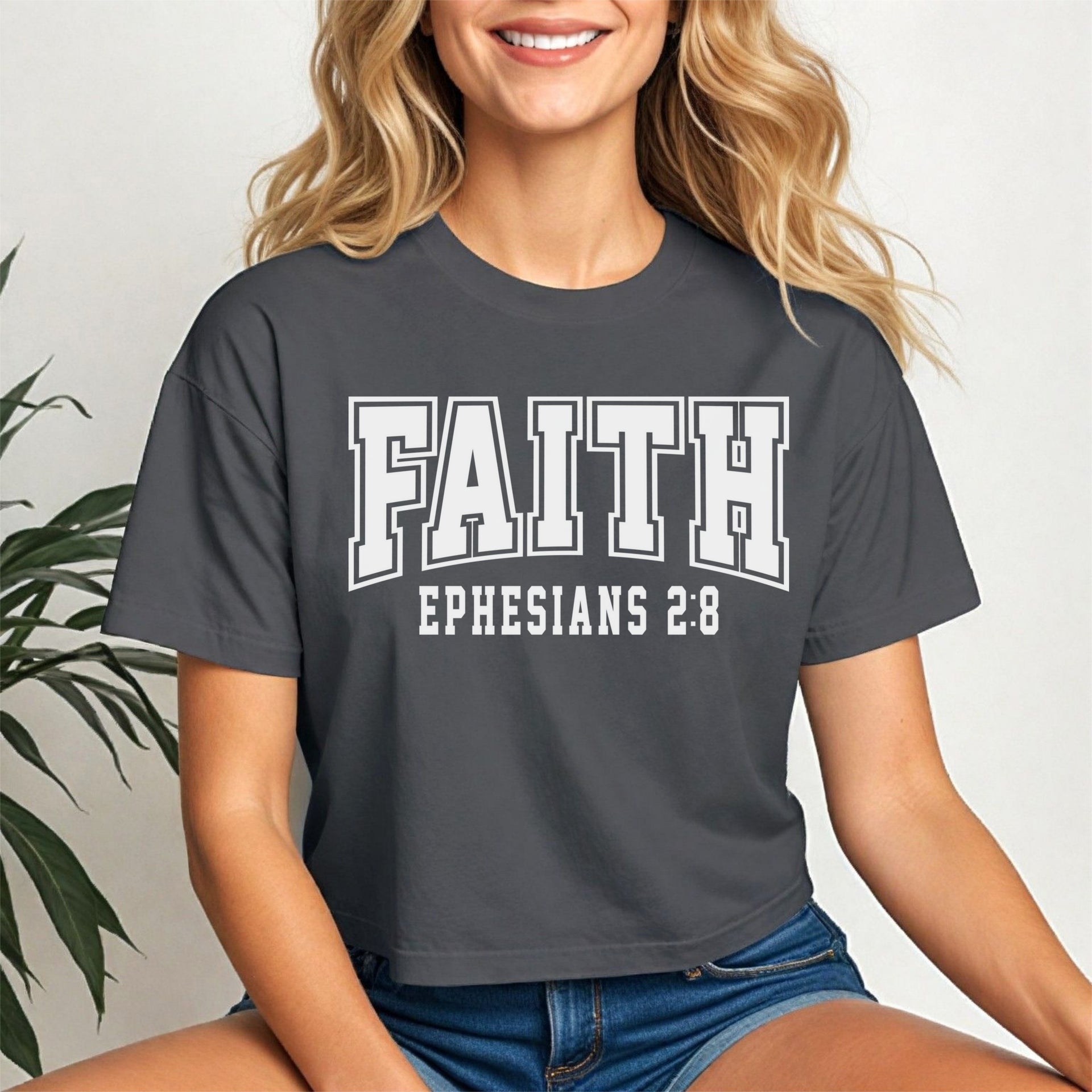 Faith Ephesians 2 8 Crop Tee displayed on a smiling woman, featuring bold text on a coal short-sleeve tee.