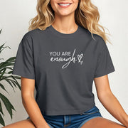 You Are Enough Script Heart Crop Tee displayed by a smiling woman in a cropped fit, showcasing a soft design.