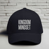 Kingdom Mindset Embroidered Flexfit Hat displayed against a simple brick wall background, emphasizing faith and intention.