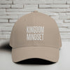 Kingdom Mindset Embroidered Flexfit Hat displayed on a flat surface against a brick wall background.