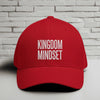 Kingdom Mindset Embroidered Flexfit Hat displayed on a table against a brick wall background.