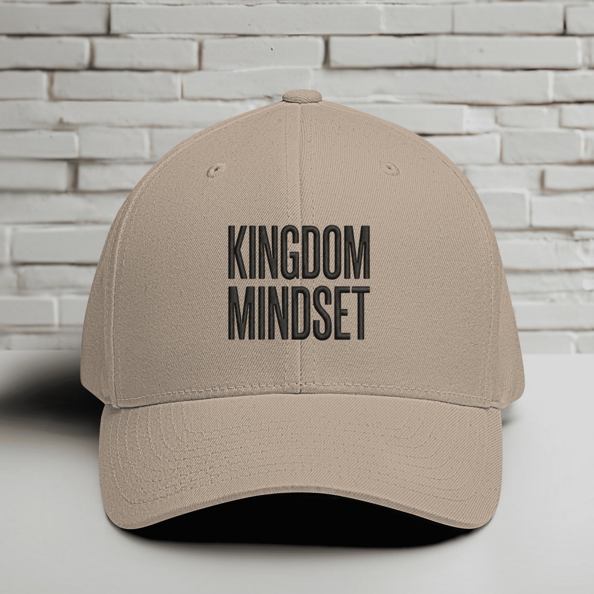 Kingdom Mindset Embroidered Flexfit Hat displayed against a brick wall background.