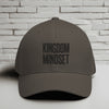 Kingdom Mindset Embroidered Flexfit Hat displayed against a brick wall background, emphasizing faith and style.