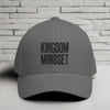 Kingdom Mindset Embroidered Flexfit Hat displayed against a textured white brick background.
