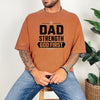 Dad Strength God First T-Shirt worn by a man sitting on a stool, featuring a vintage design and relaxed fit.
