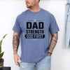 Man wearing Dad Strength God First T-Shirt, showcasing faith and strength in a casual setting.