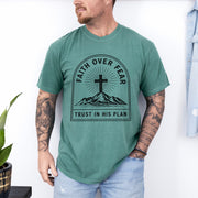 Faith Over Fear Trust In His Plan Comfort Colors T Shirt worn by a man with tattoos and a green backdrop.