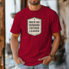 Man Of God Husband Father Leader T Shirt worn by a man, showcasing a badge-style design in a red color.