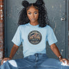 Woman wearing a light blue 250 Years America Badge T-Shirt with a vintage badge design.
