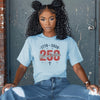 A young woman wearing the Blessed & Free 250 T-Shirt featuring patriotic design and comfortable fit.