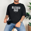 Man wearing a Blessed Dad Cross T Shirt, holding a mug, showcasing a bold design and relaxed style.