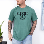 Man wearing a Blessed Dad Cross T Shirt in green, featuring a bold black text design celebrating fatherhood and faith.