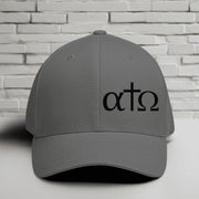 Alpha Omega Cross black hat with Greek letters on a gray Flexfit cap against a brick background.