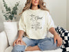 Woman wearing a Love God T Shirt with Mark 12:30 design, showcasing comfort and faith in a cozy setting.