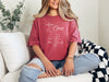 love God t shirt worn by a woman on a couch, featuring a cross design and scripture Mark 12:30.