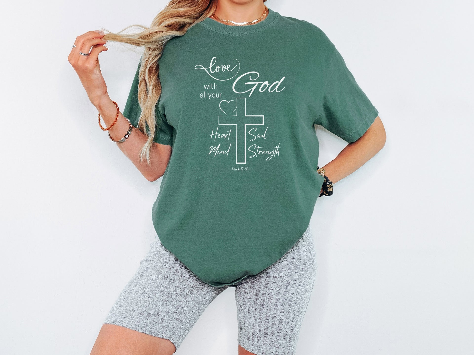 love God t shirt featuring a cross and scripture Mark 12:30 on a model wearing a relaxed green tee.