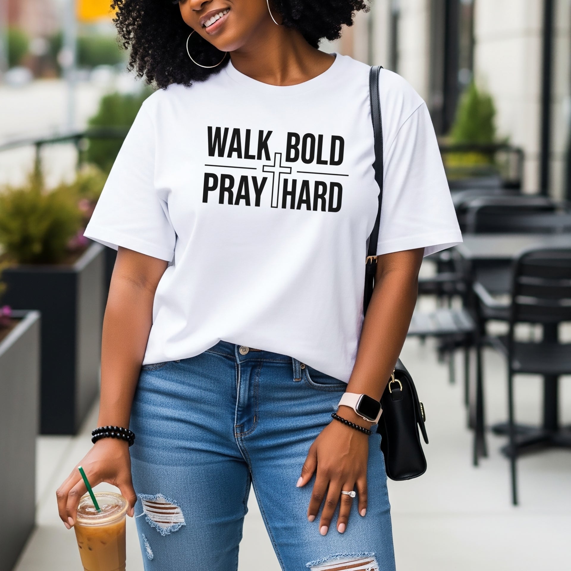 Woman wearing Walk Bold Pray Hard Christian cross t shirt, showcasing faith and style in a casual urban setting.
