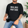 Walk Bold Pray Hard Christian cross t shirt worn by a man holding a mug, featuring bold text design on a black tee.