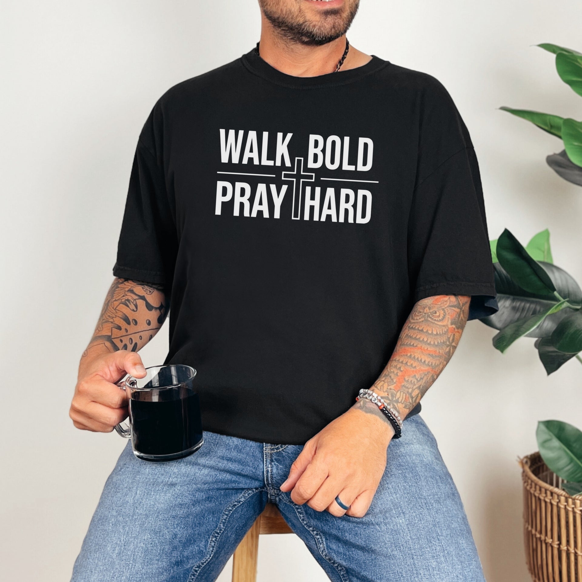 Walk Bold Pray Hard Christian cross t shirt worn by a man holding a mug, featuring bold text design on a black tee.