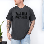 A man wearing a Walk Bold Pray Hard Christian cross t shirt, showcasing a bold design and relaxed fit.